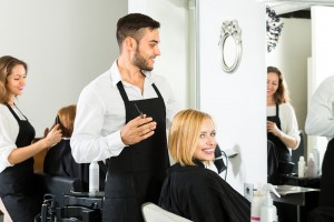 Vrouw krijgt een kappersbeurt door mannelijke kapper en glimlacht naar de camera